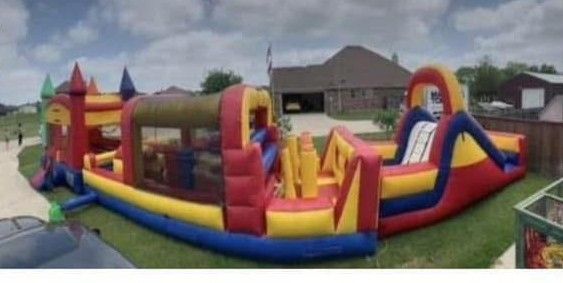 Colorful inflatable bounce slide on a grassy yard beside a brick house under a cloudy sky