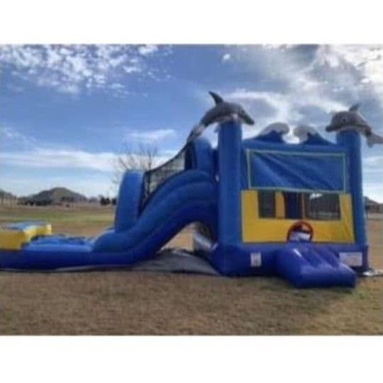Colorful inflatable bounce slide on a grassy yard beside a brick house under a cloudy sky
