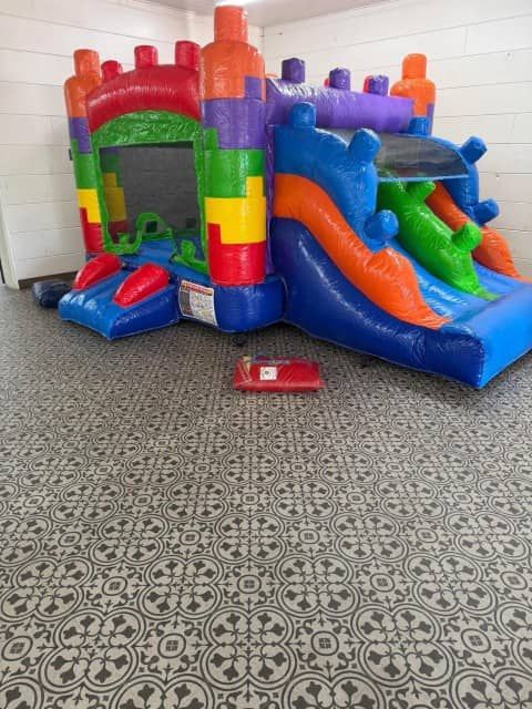 Colorful inflatable bounce house with slides in an indoor room on patterned carpet