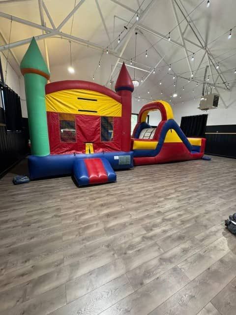 Colorful inflatable bounce house and slide in an indoor play area with a large open floor