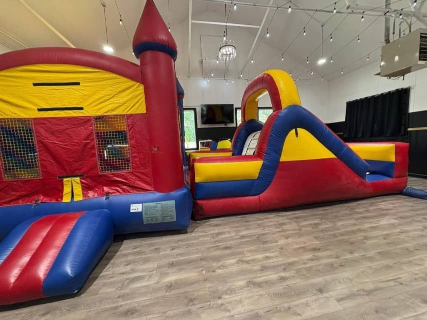 Colorful inflatable bounce house and obstacle course set up in an indoor play space