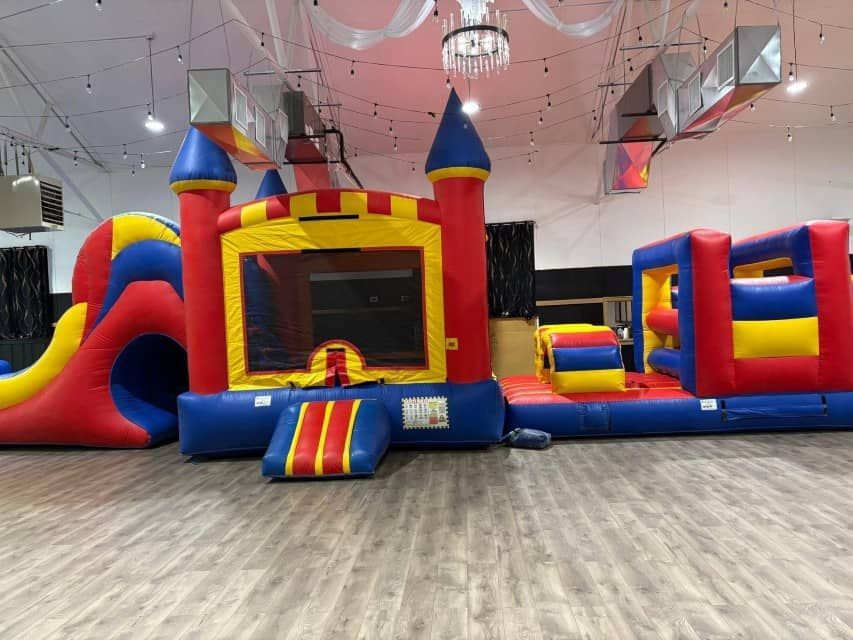 Indoor inflatable bounce house with colorful slides and play areas in a large room