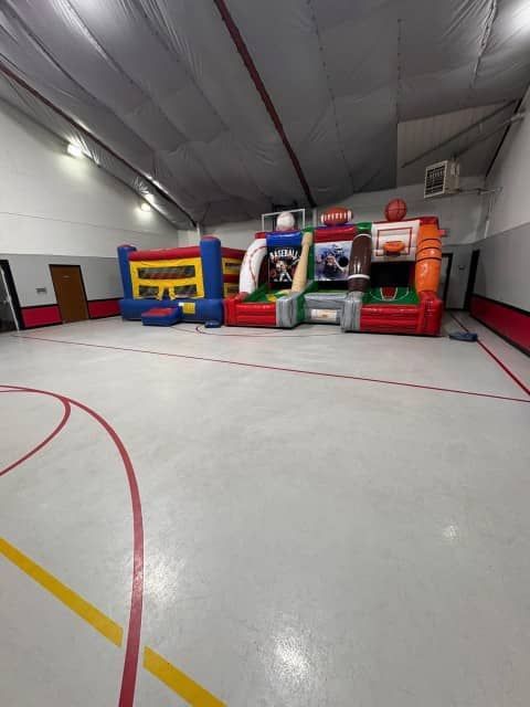 Indoor gym with colorful inflatable obstacle course set up against a wall.