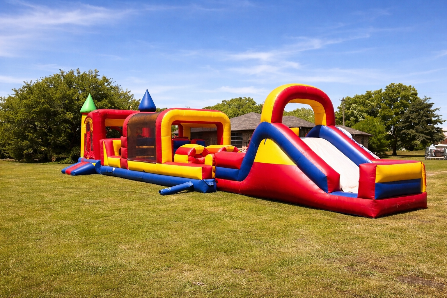 Colorful inflatable obstacle course on a grassy field under a blue sky.
