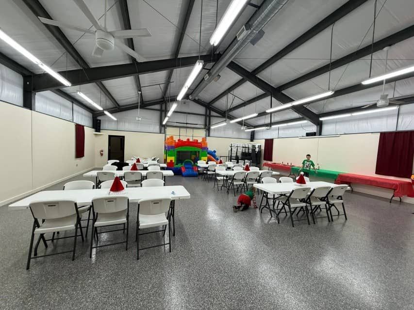 Indoor event hall with tables, chairs, and a colorful bounce house at the back.