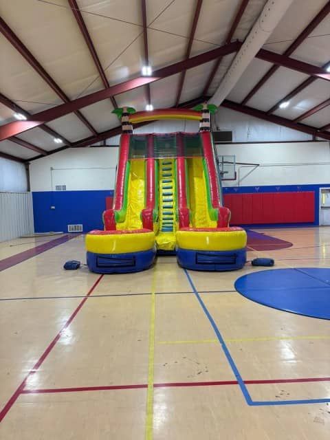 Colorful inflatable slide in an empty gymnasium with polished hardwood floor