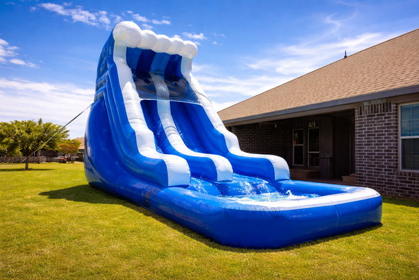 Blue and white inflatable water slide on a grassy lawn with a house in the background.