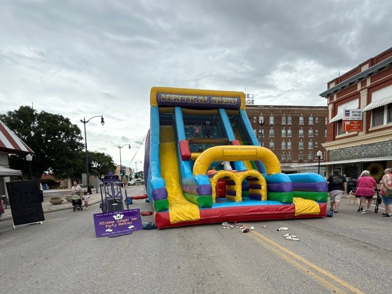 Colorful inflatable obstacle course on a city street with a few people walking nearby