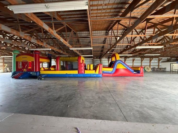 Colorful inflatable bounce house in a large barn-like pavilion with exposed wooden rafters