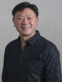 A man in a black shirt is smiling for the camera.