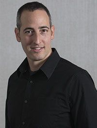 A man in a black shirt is smiling for the camera.