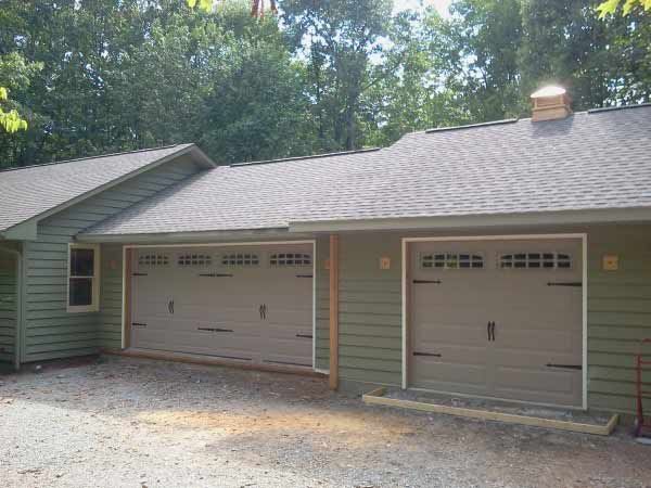A house with two garage doors and a chimney on the roof.