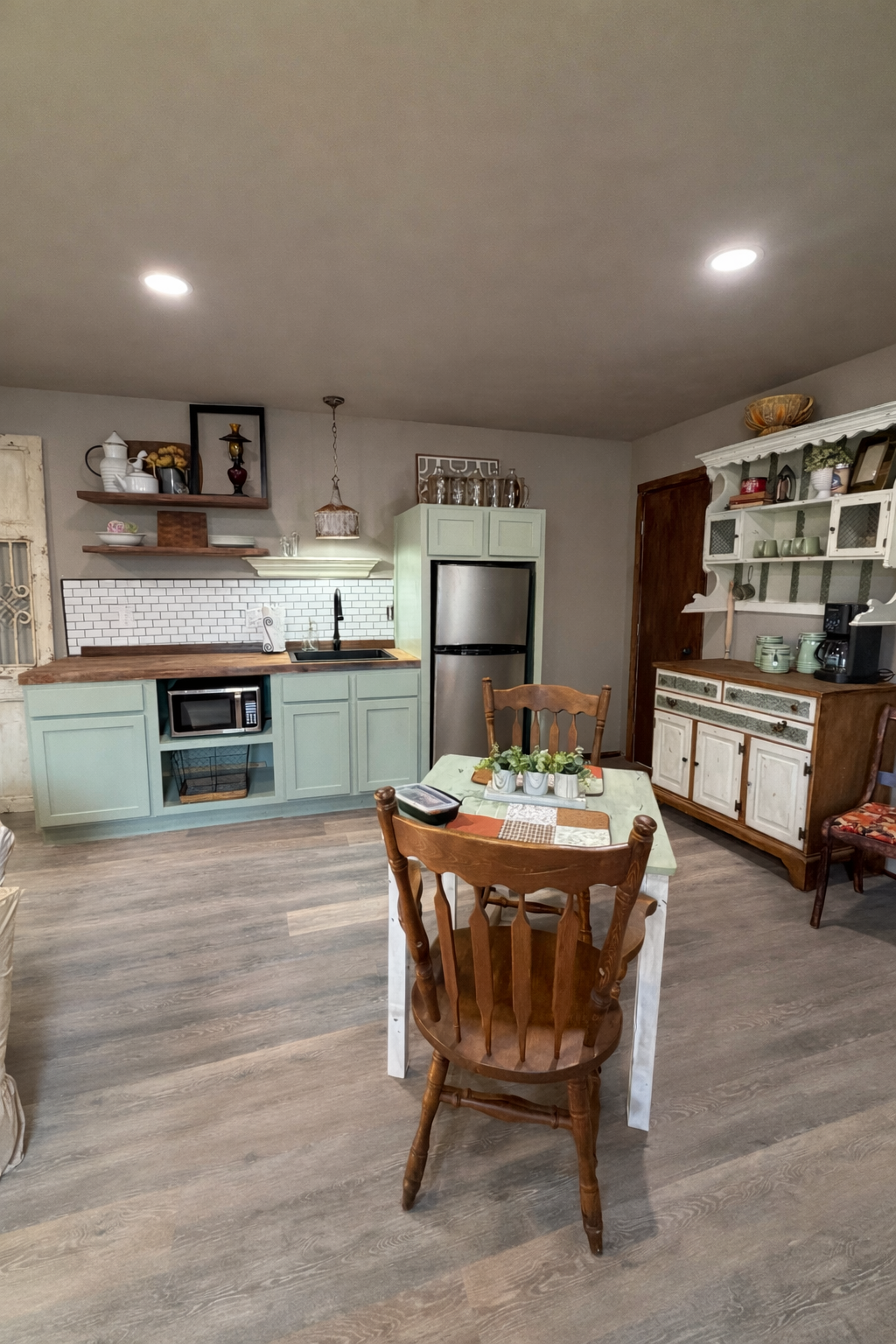 Spacious kitchen with mint cabinets, wood floor, dining table, and white hutch.