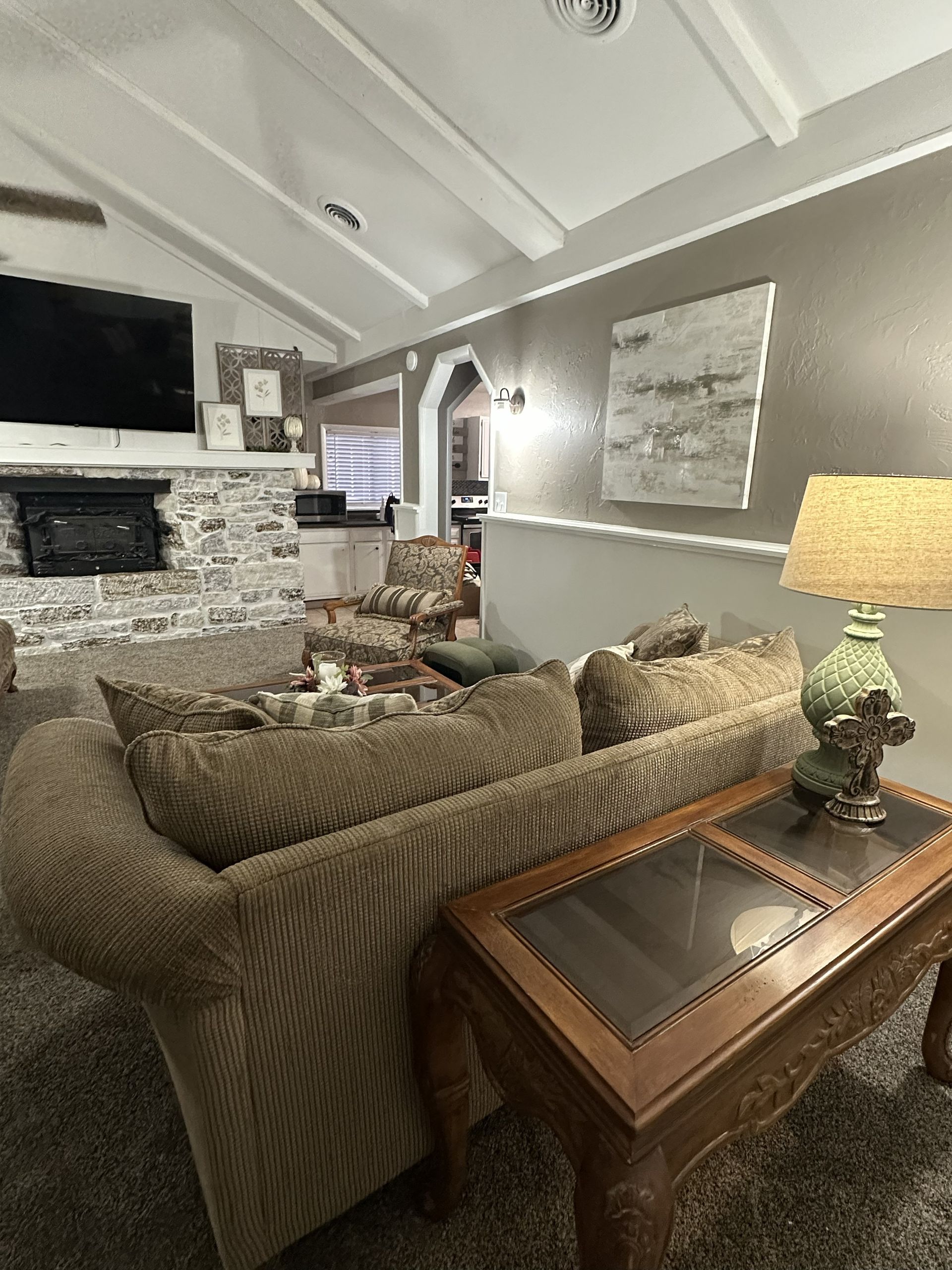 Living room with beige couch, stone fireplace, and artwork on a gray wall.