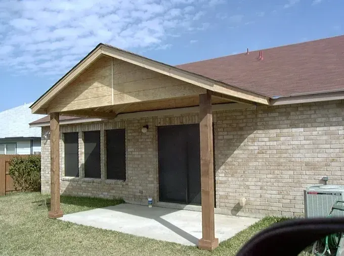 Single-story brick house with a small front porch and wooden posts under a clear blue sky