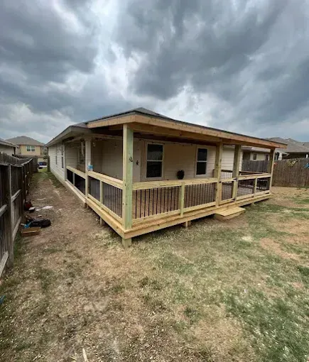 Single-story house with a wraparound porch, seen from the yard under cloudy skies.