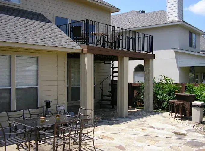 Patio with outdoor dining table, grill, and second-story deck on a beige house