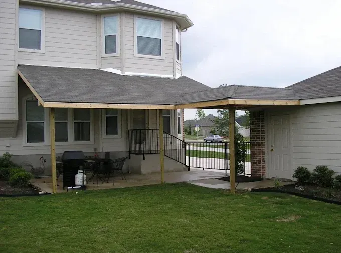 Two-story townhouse with covered patio, lawn, and a fenced gate between units