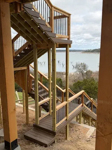 Wooden outdoor staircase and deck overlooking a calm lake on a cloudy day