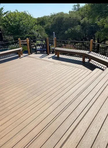 Wooden deck walkway with railings overlooking green trees on a sunny day
