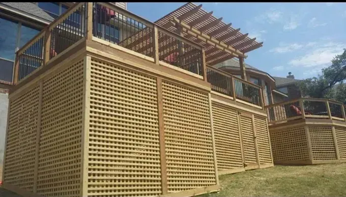 Wooden lattice retaining walls and deck on a grassy hillside under a blue sky
