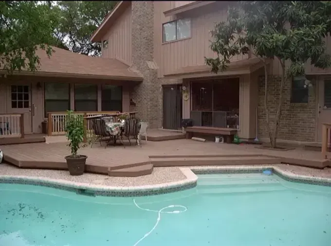 Backyard patio with a swimming pool beside a two-story house and outdoor seating area