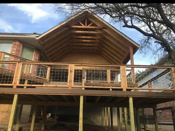 Wooden deck and roofed porch on a raised house with trees overhead