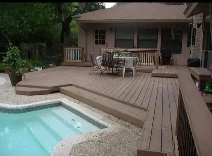 Backyard deck with pool, lounge seating, and house patio surrounded by trees