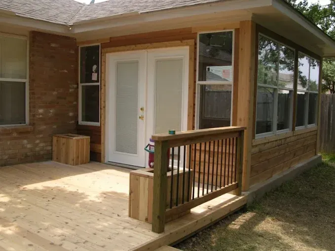 Back patio with white French doors, wooden deck, and railing beside a brick house