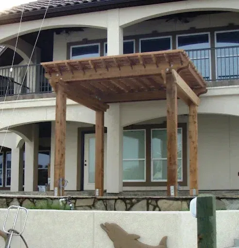 Wooden pergola structure in front of a two-story house with a balcony