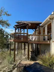 Wooden deck and pergola on a house overlooking a dry hillside under a clear blue sky