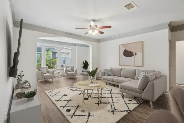 Living room with light gray sofa, rug, chairs, and coffee table, with a view to a sunroom.