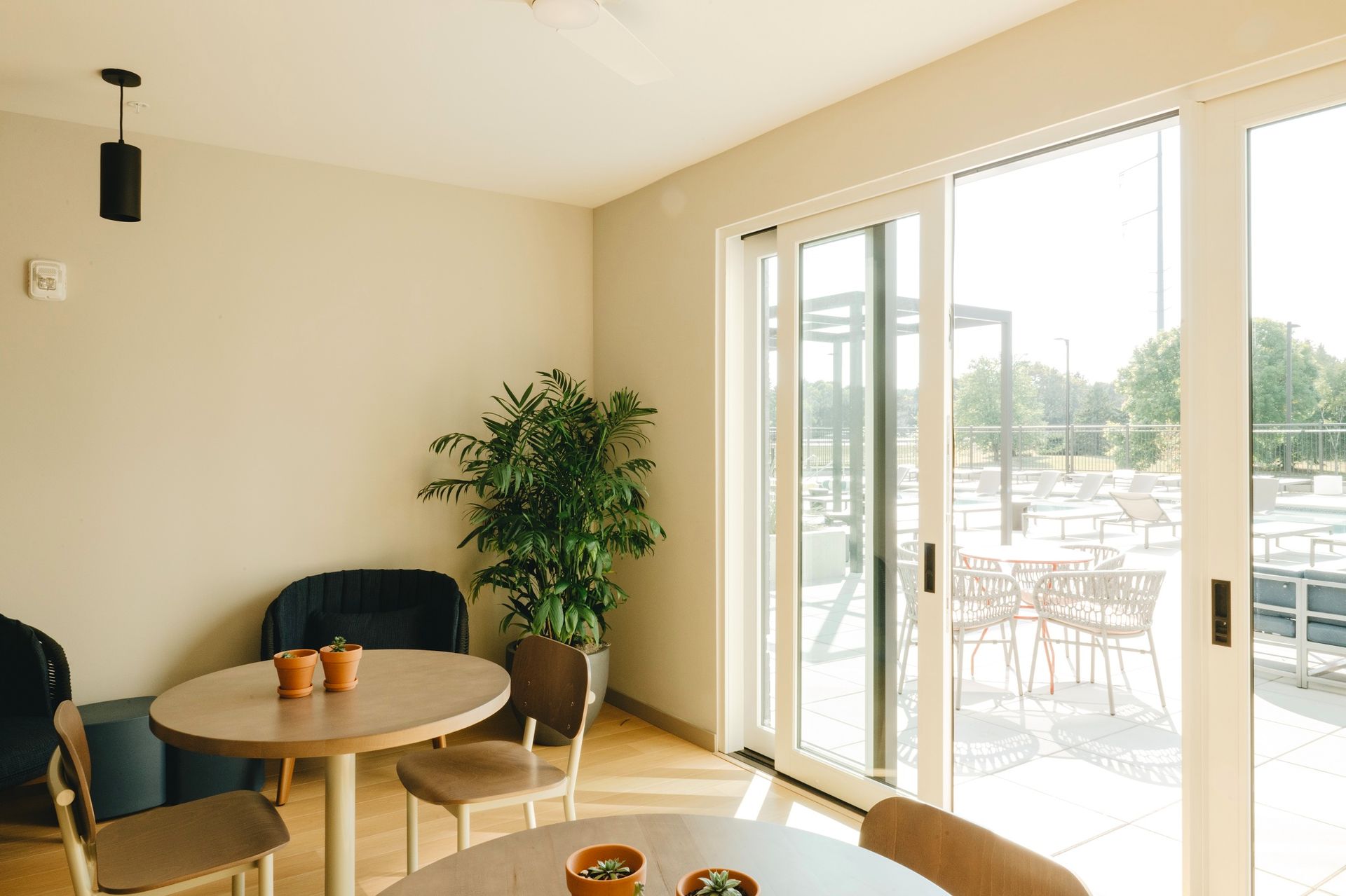 Indoor seating area with a view of an outdoor patio through sliding glass doors. Tables and chairs at Revelry in Madison, WI.