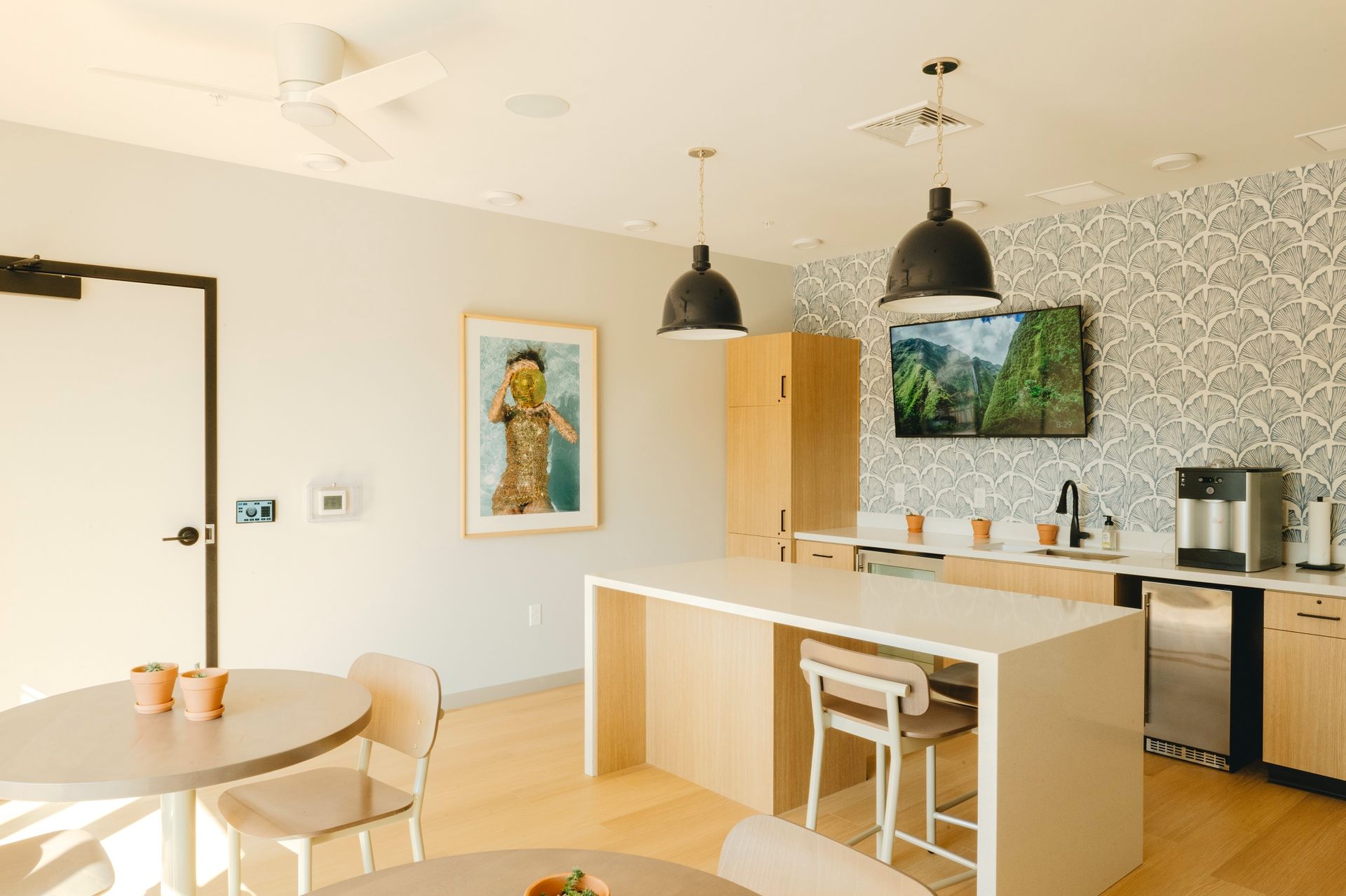 Modern kitchen/breakroom with a white island, two round tables, and a tv at Revelry in Madison, WI.