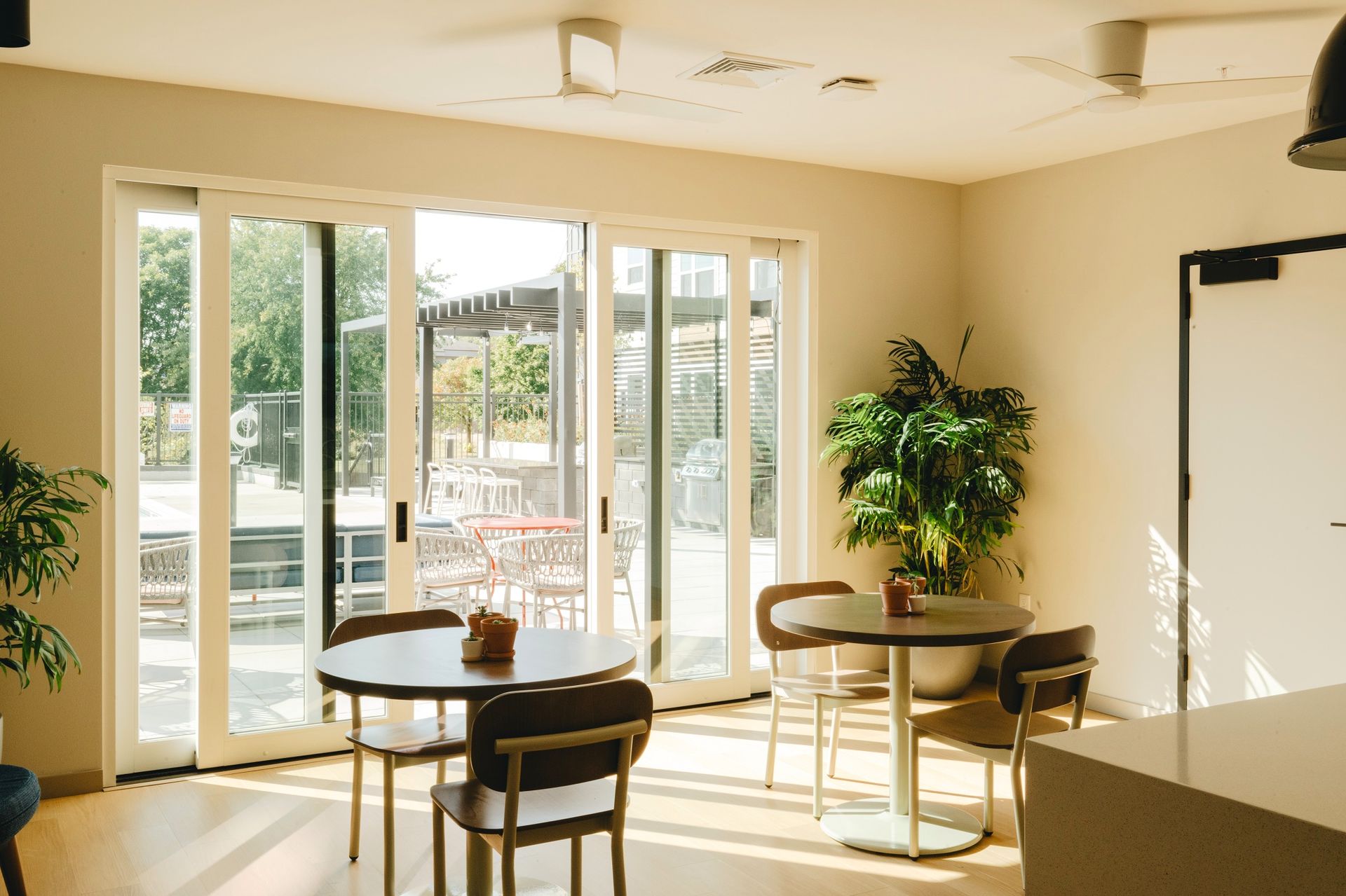 Interior of a cafe with round tables and chairs. Sliding doors lead to an outdoor seating area at Revelry in Madison, WI.