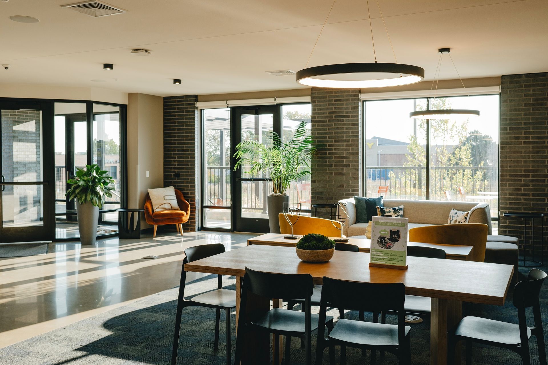 A spacious, well-lit lounge with tables, seating, brick walls, large windows, and greenery in Middleton.