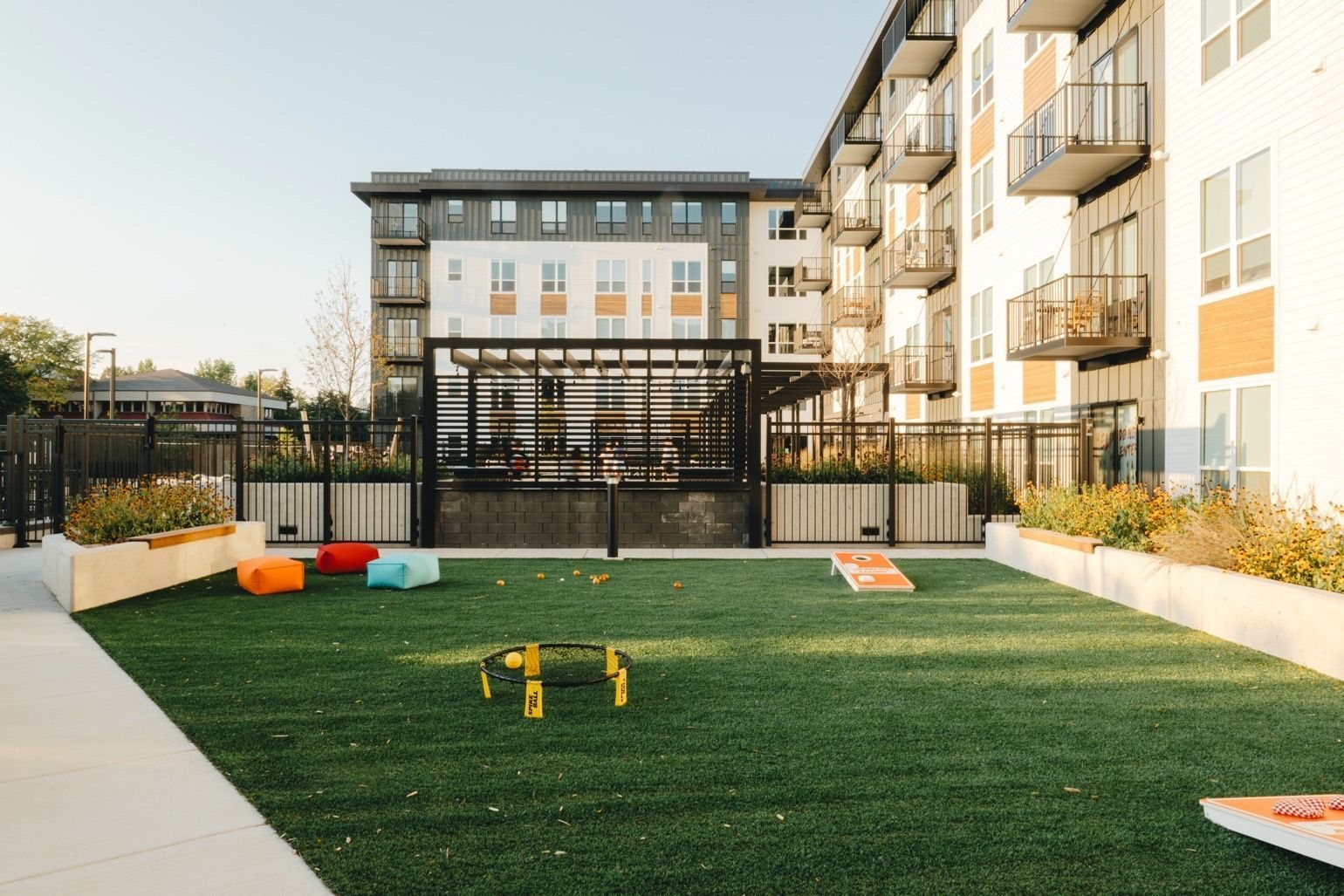 A courtyard with artificial turf, game setup, colorful seating, and modern apartments at Revelry in Madison, WI.