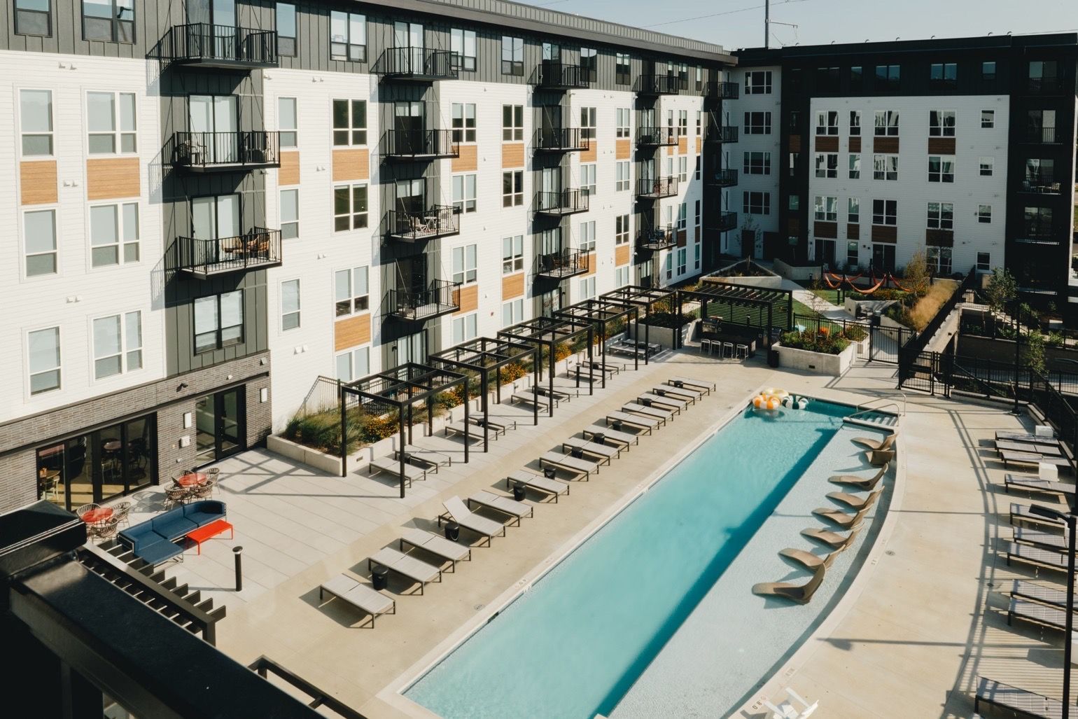 Apartment complex with a long pool and lounge chairs in the courtyard at Revelry in Madison, WI.