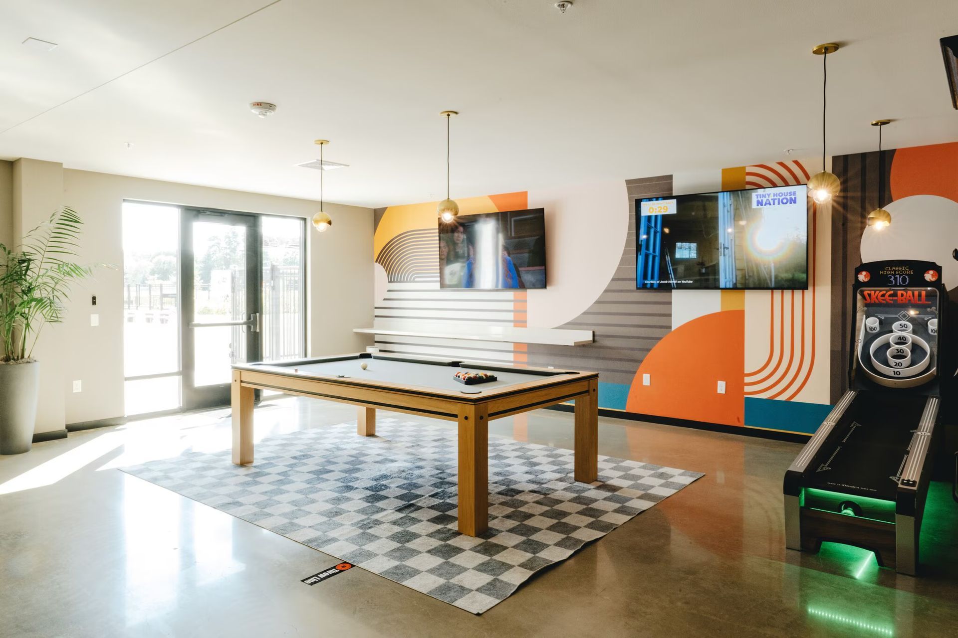 Game room with pool table, arcade game, TVs, and colorful mural at Revelry in Madison, WI.