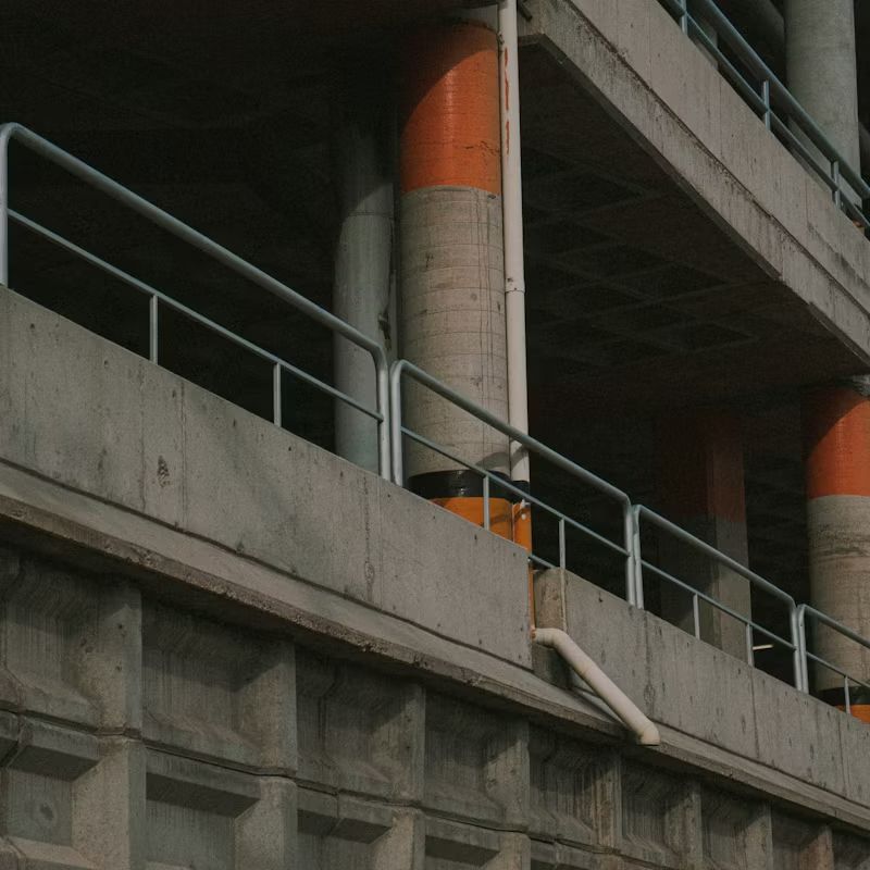 Concrete overpass with gray railings and orange-and-white support pillars above a roadway
