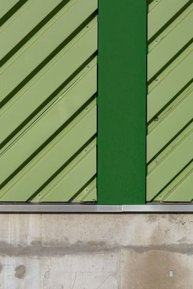 Green slatted panel with diagonal trim above a concrete base and a vertical dark green strip