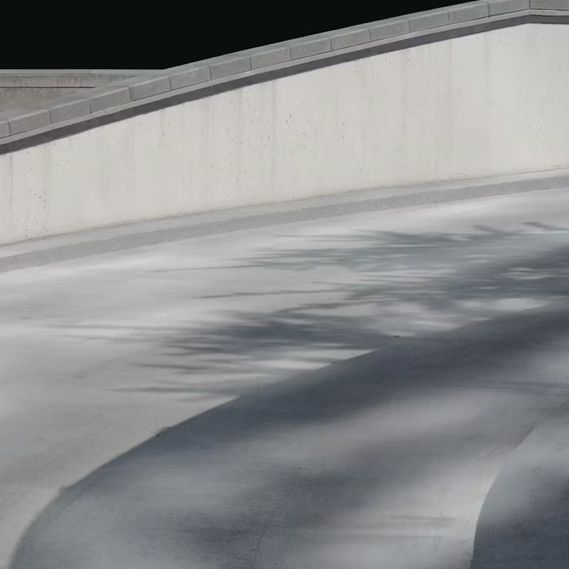 Curved concrete ramp or walkway with long tree shadows in bright sunlight