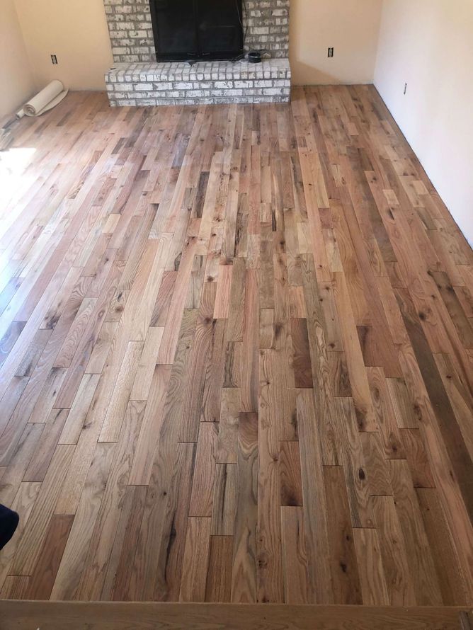 Completed hardwood flooring in a living room with a fireplace