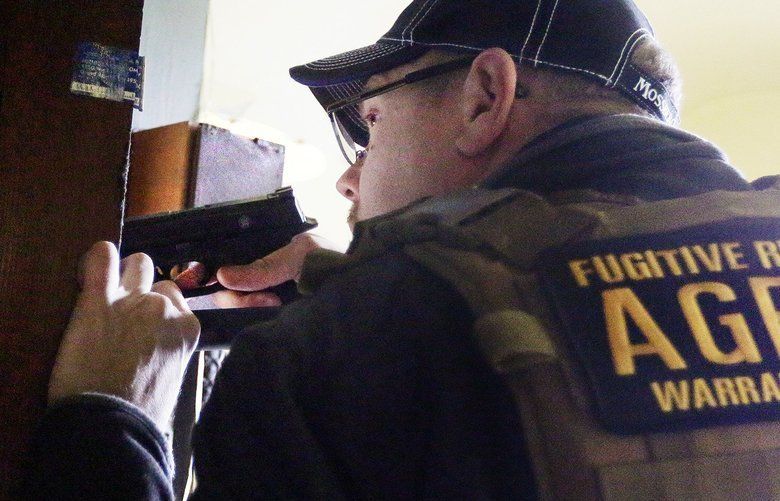 Man with a gun, in tactical vest labeled 