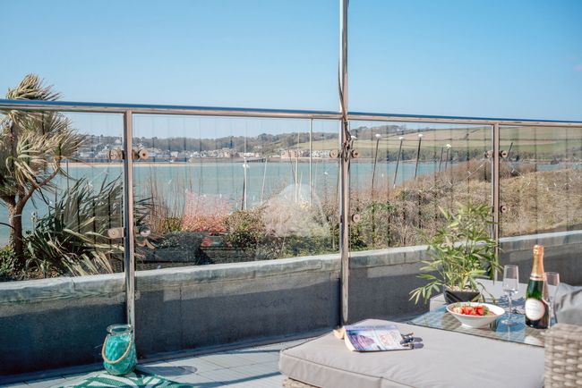 Patio table with sunflowers overlooking a calm waterfront and distant houses
