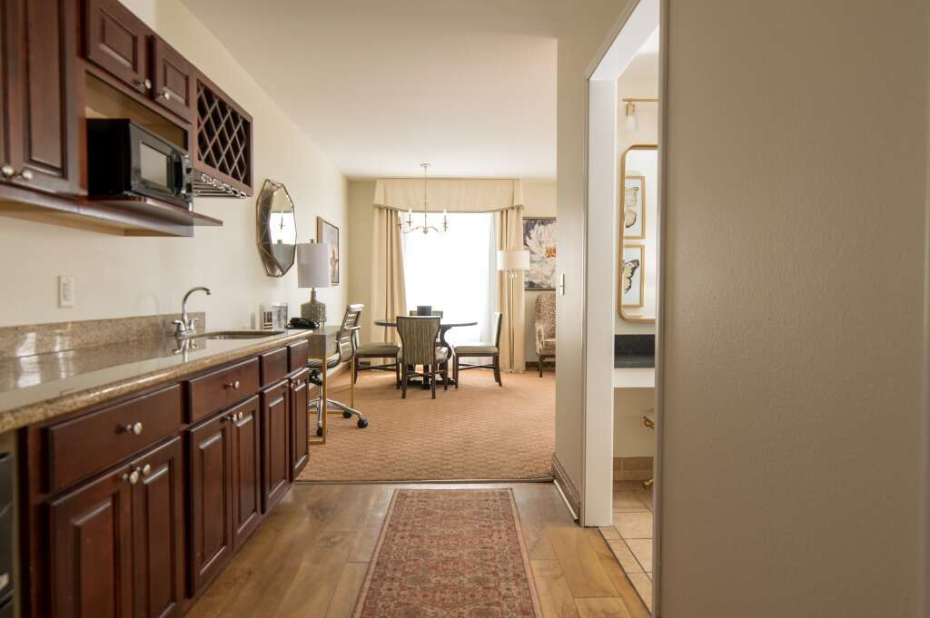 Kitchen area with dark wood cabinets, leading to dining area with a table and chairs.