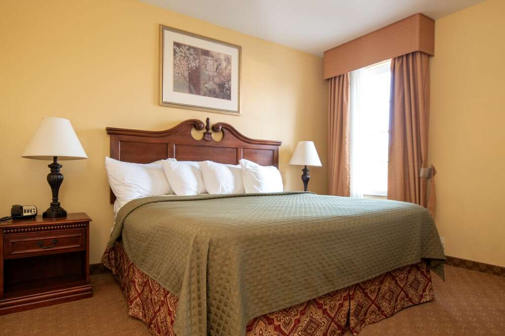 Hotel room with a king-sized bed, lamps on nightstands, and a window with curtains.