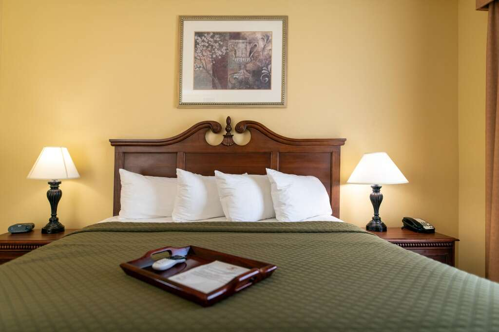 Hotel room with a king-sized bed, two nightstands with lamps, and a painting above the bed.