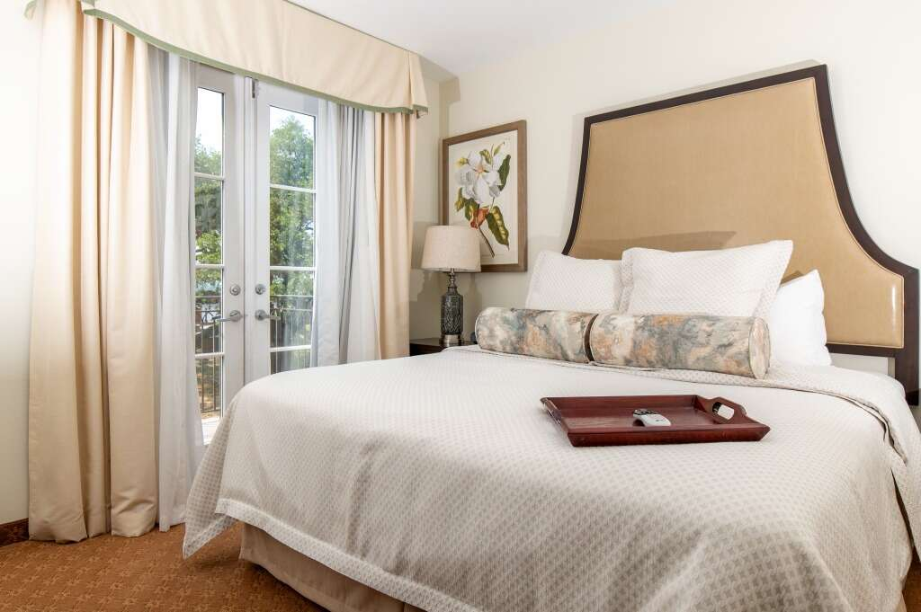 Bedroom with a large bed, French doors, and neutral colors.
