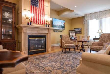 Cozy living room with fireplace, American flag, and furniture. Warm colors, ornate details.